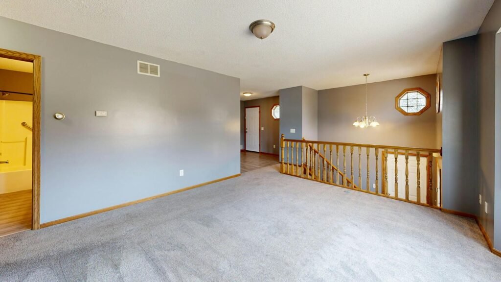 A staged living room with neutral seating, good light, and an obvious walking path.
