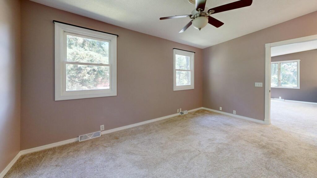 A staged living room with a soft neutral wall color and simple furnishings