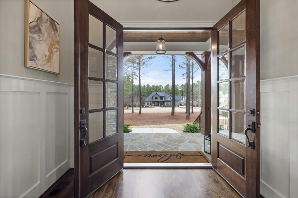 A clean front entry with a fresh doormat, planters, and polished door hardware.