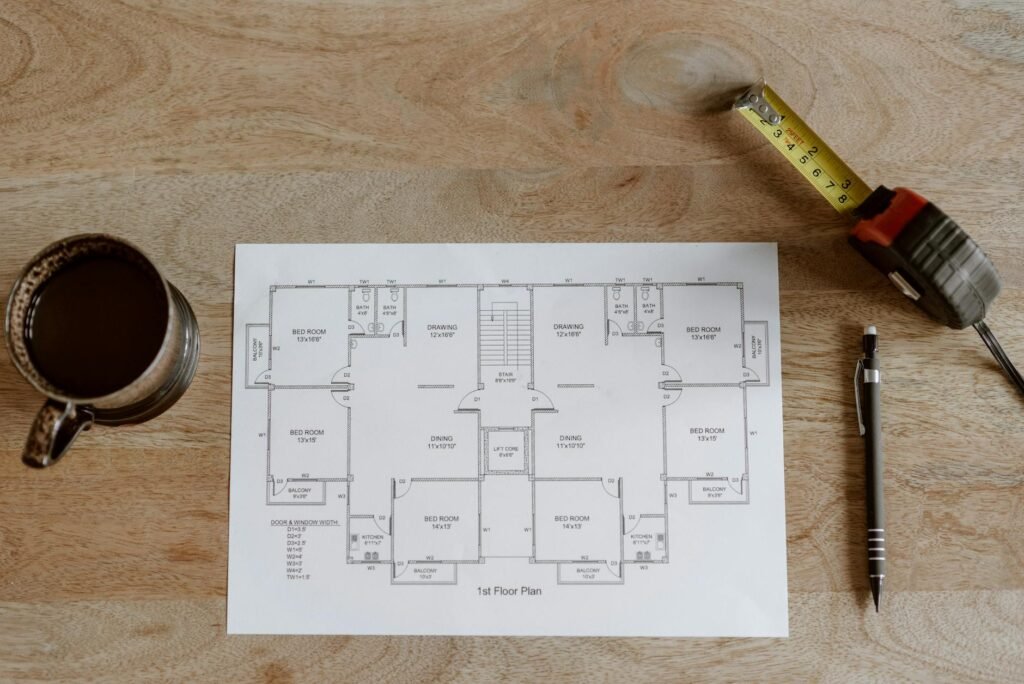 A person measuring a living room and marking furniture sizes on the floor with tape.