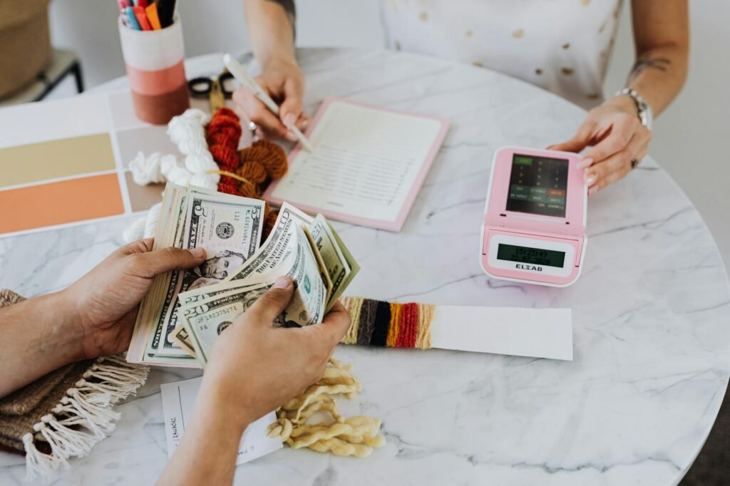 A desk with a calculator, receipts, notebook, and decor samples for a room budget