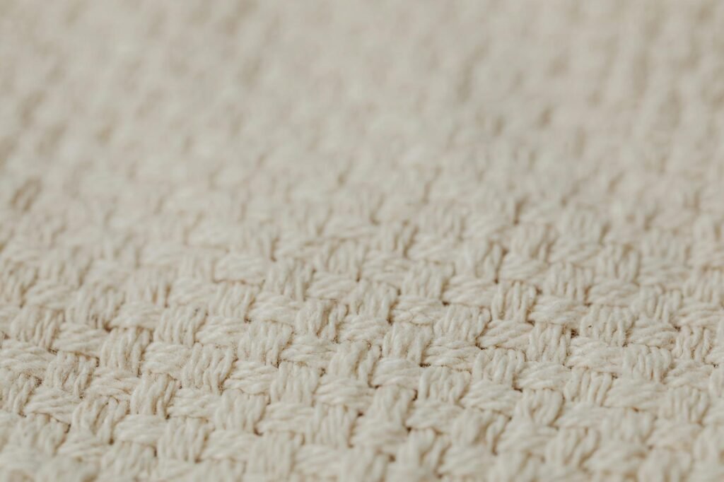 A close-up composition of linen, wool, wood, ceramic, and brass home materials