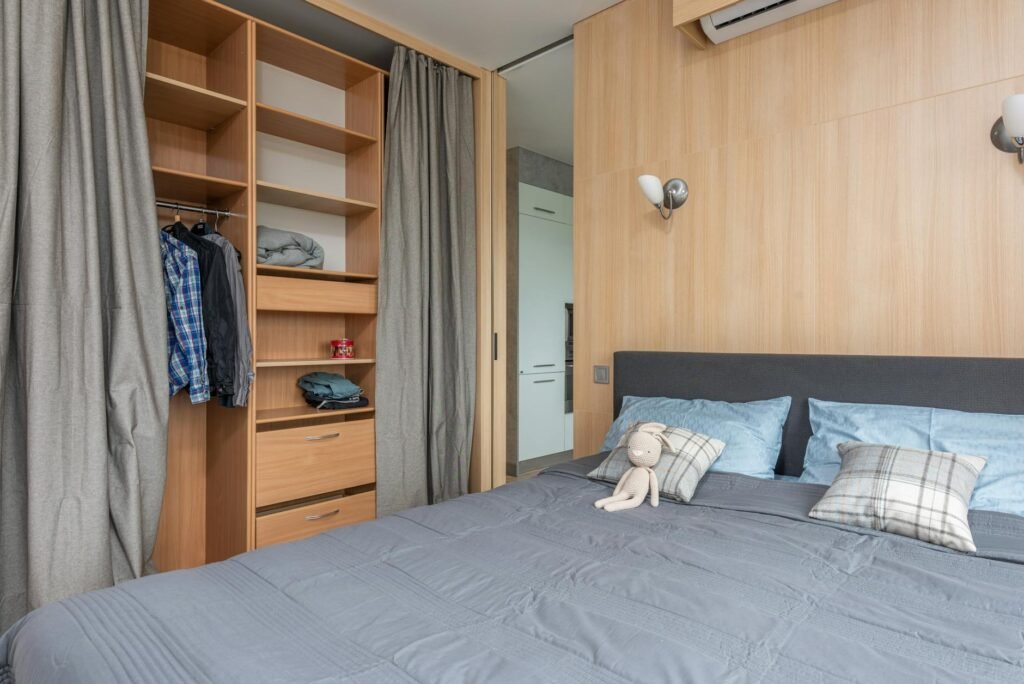 A bedroom corner with hidden laundry storage and neatly organized under-bed bins.