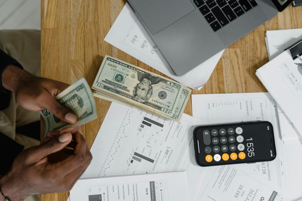 A person reviewing listing photos with receipts and a calculator on a desk