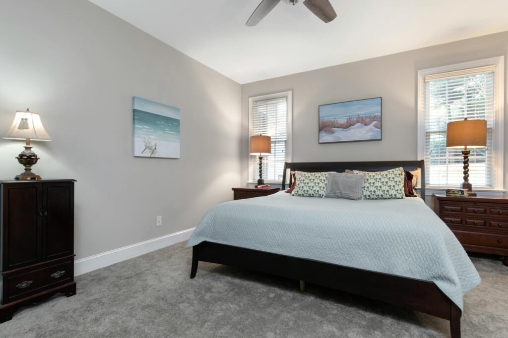 A real estate photographer capturing a staged bedroom with bedside lamps adding depth to the scene.
