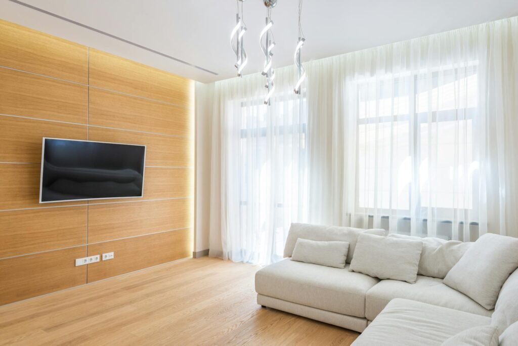A living room window with curtains hung high and wide to let in more daylight.