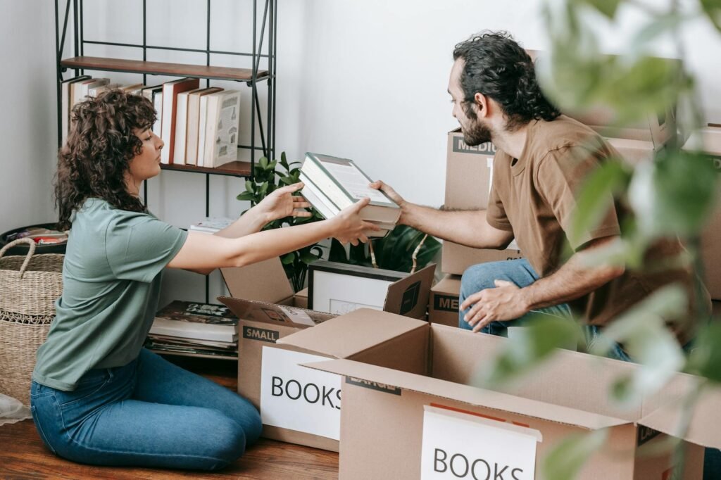 A homeowner packing framed photos and decor into labeled bins before listing a house.