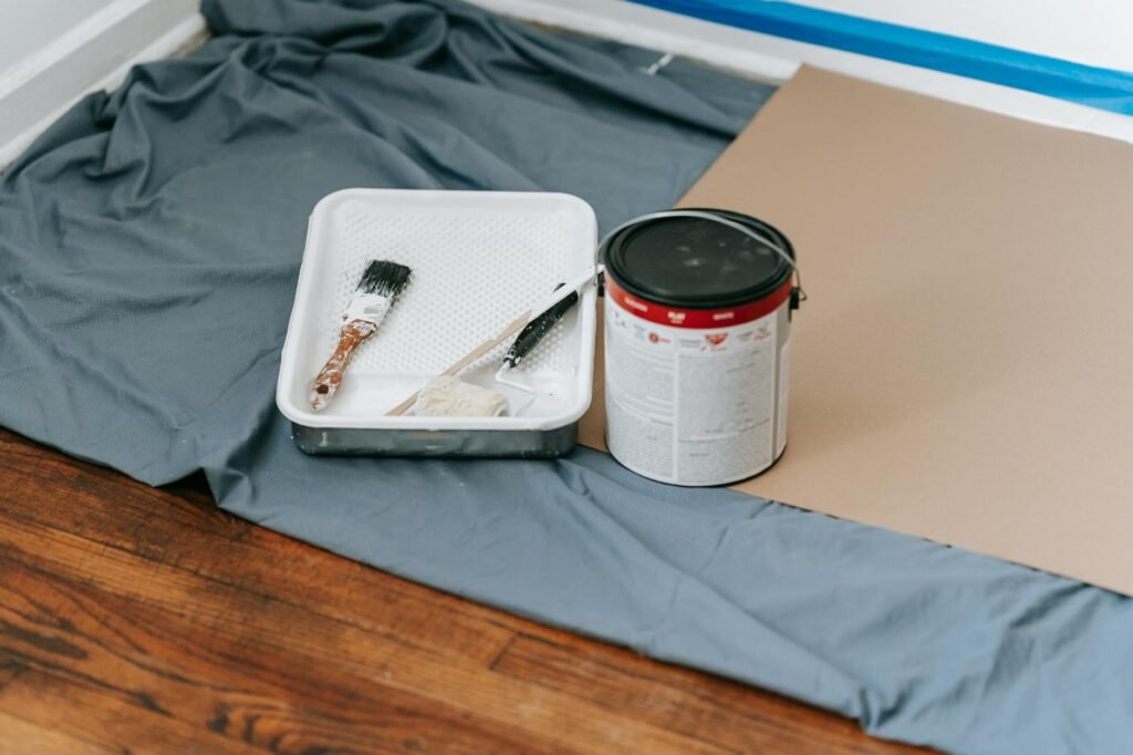 Painting supplies, a notebook, and a calculator on a protected floor