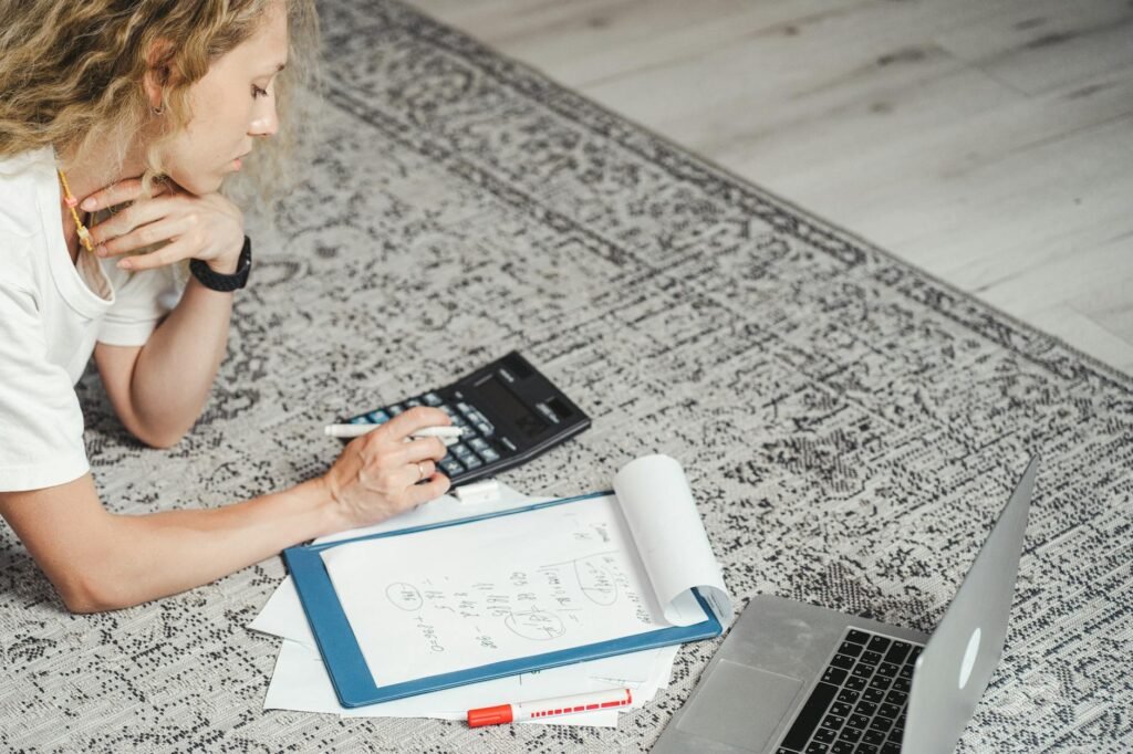 A notebook, calculator, measuring tape, and decor samples laid out on a coffee table.